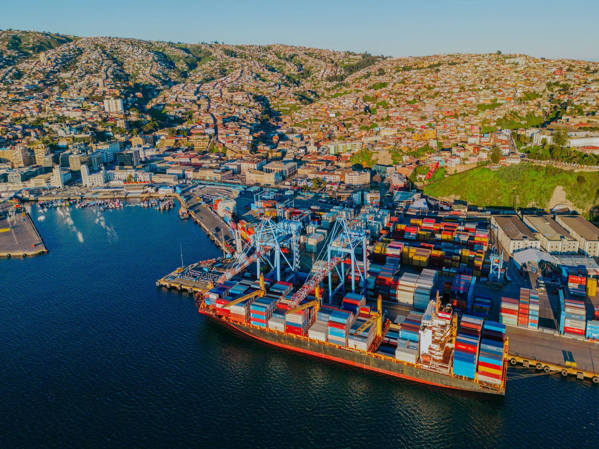 Schiff mit Containern und Stadt auf dem Berg im Hintergrund